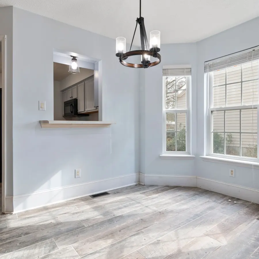 Bright freshly painted room with white walls, bay windows and a chandelier